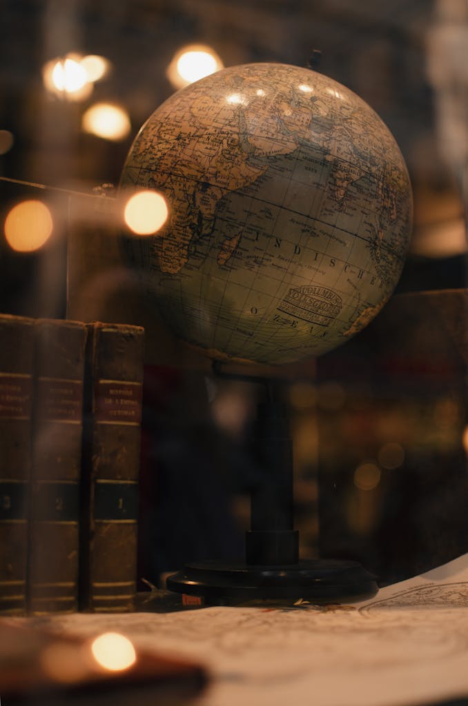 Through glass of world globe and ancient books placed behind transparent display in museum